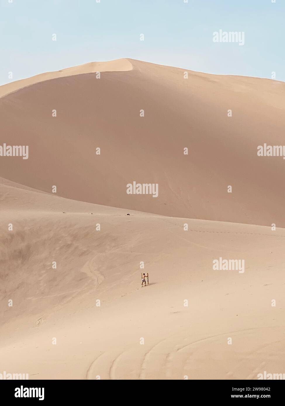 A person climbing a dune in a vast desert Stock Photo - Alamy