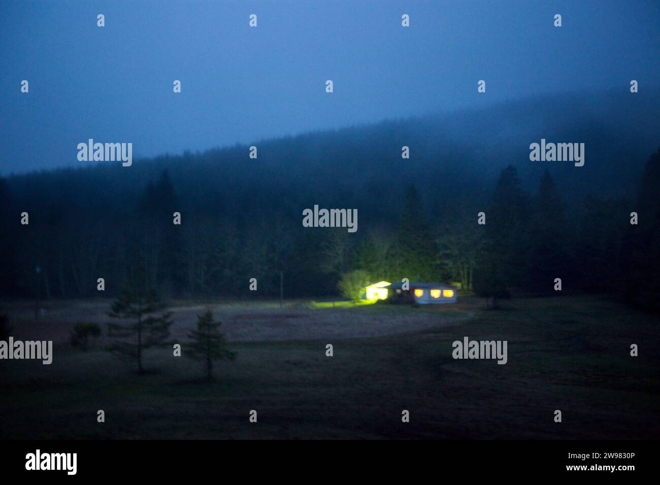 A house sits in the hills in fog at night near Sequim, Wa. Stock Photo