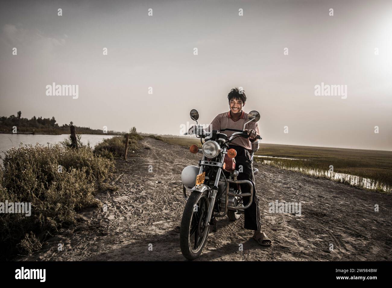 Central Asian man with his motorcycle Stock Photo