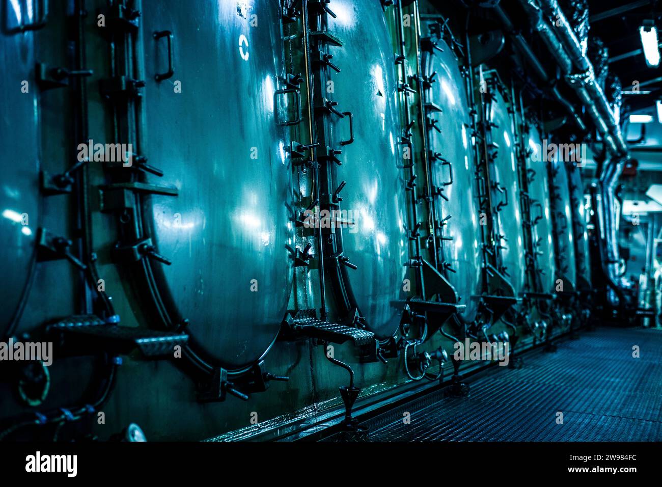 Dimly lit chambers inside the engine room on a container ship Stock