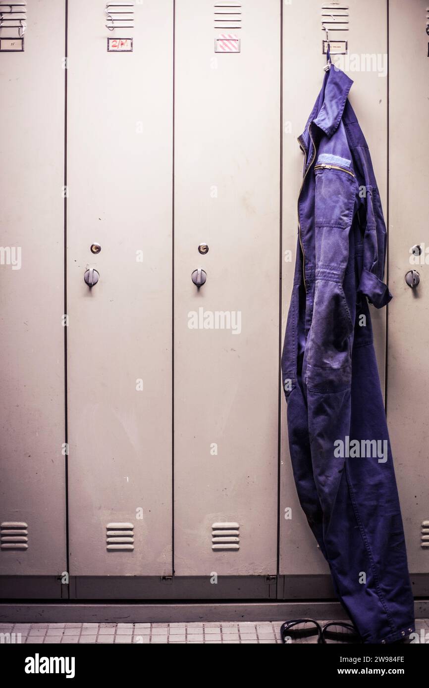 worker's overalls hanging on a hook in a locker room. Stock Photo