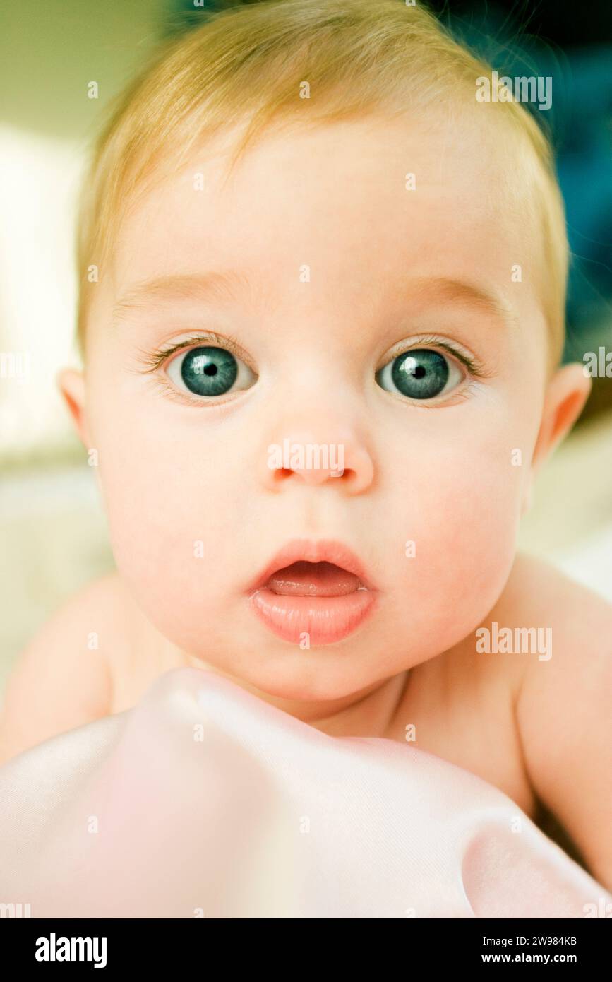 Young baby looking into camera with big eyes. Stock Photo