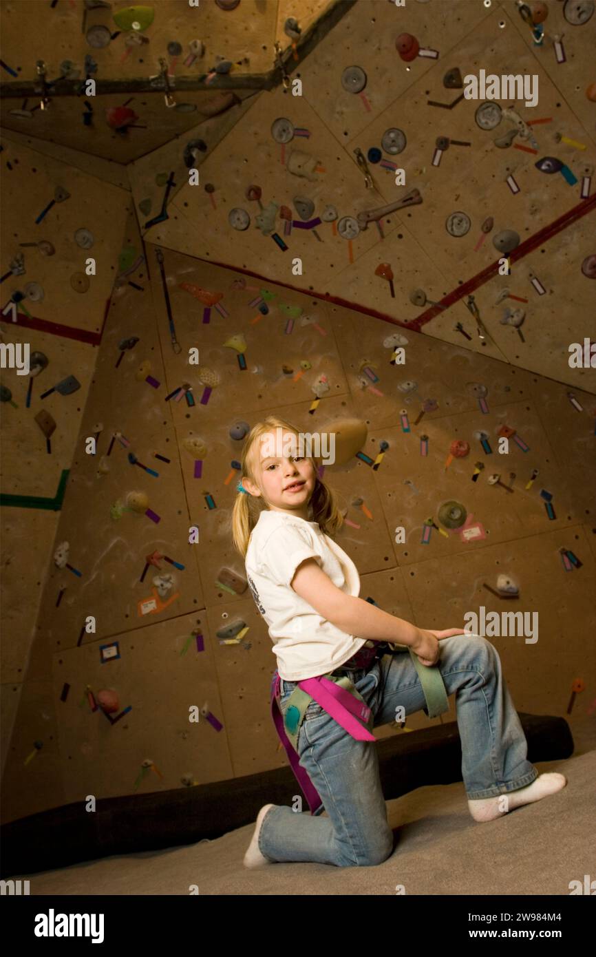 Young girl kneeling at a rock climbing gym, Santa Fe, New Mexico Stock