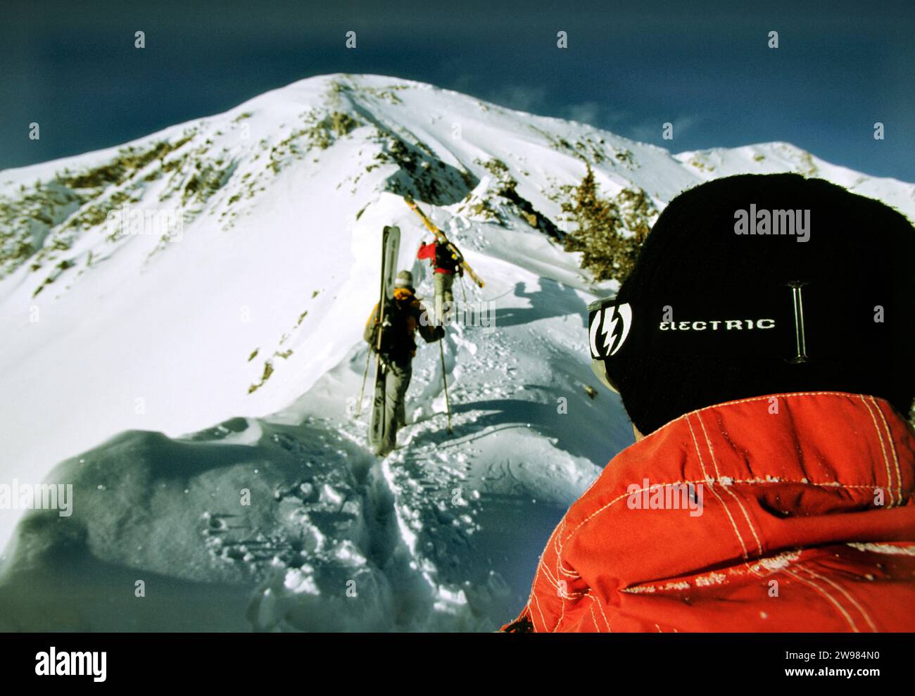 A close up photo of one skier hiking a mountain with a group. Stock Photo