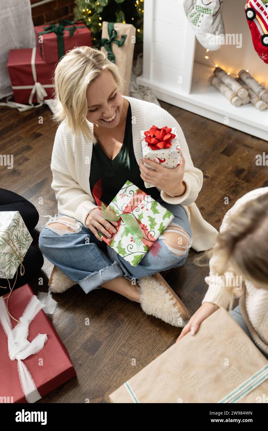 Woman smiling and looking at a wrapped christmas gift Stock Photo