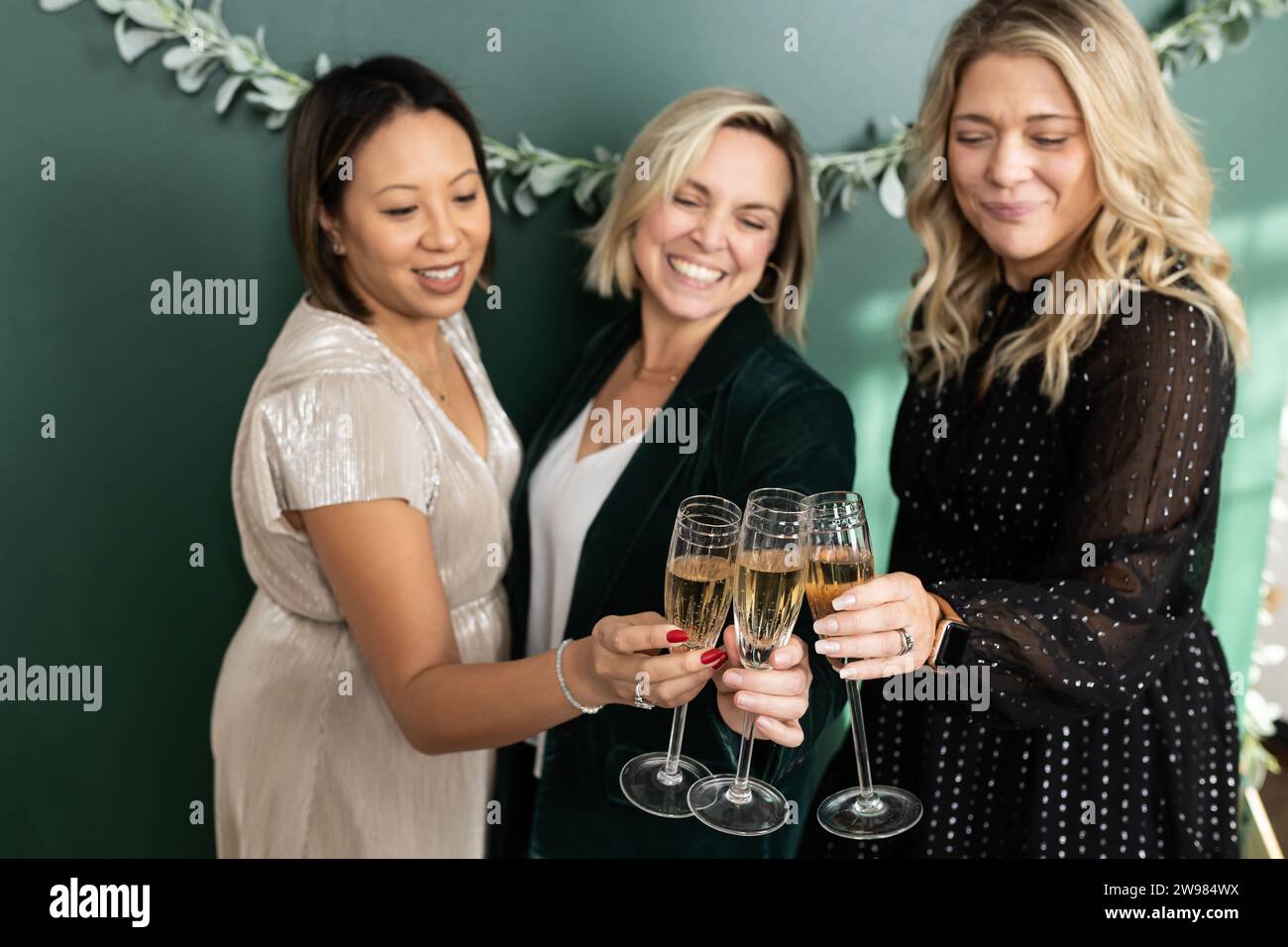 Three women holding champagne flutes toasting each other Stock Photo