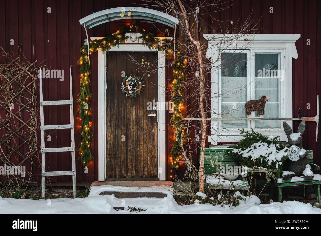 Wooden front door with garland lights and christmas tree at home Stock Photo