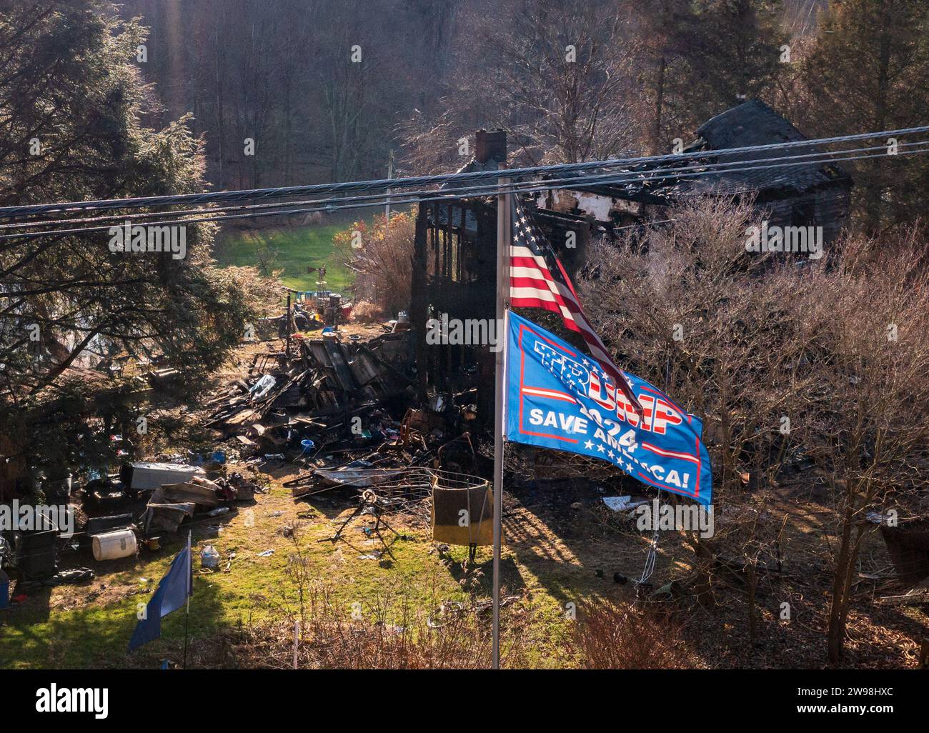 Morgantown, WV - 24 December 2023: Burned out home behind a US and Trump 2024 flag as concept for election campaign collapse Stock Photo