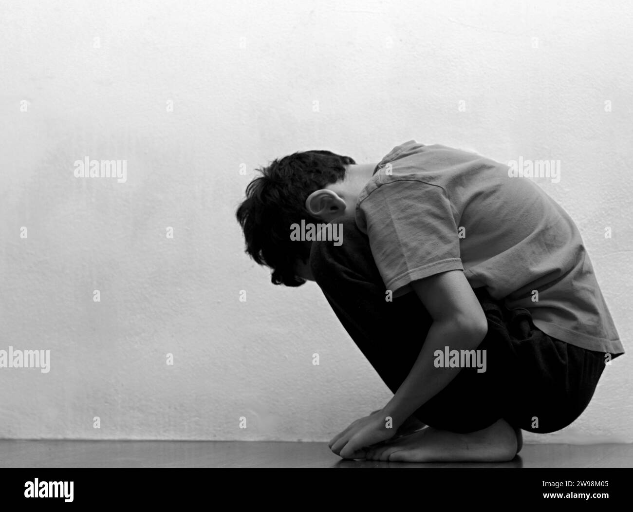 boy praying in poverty on the floor stock image with no help crying alone and all by himself on white background stock photo Stock Photo