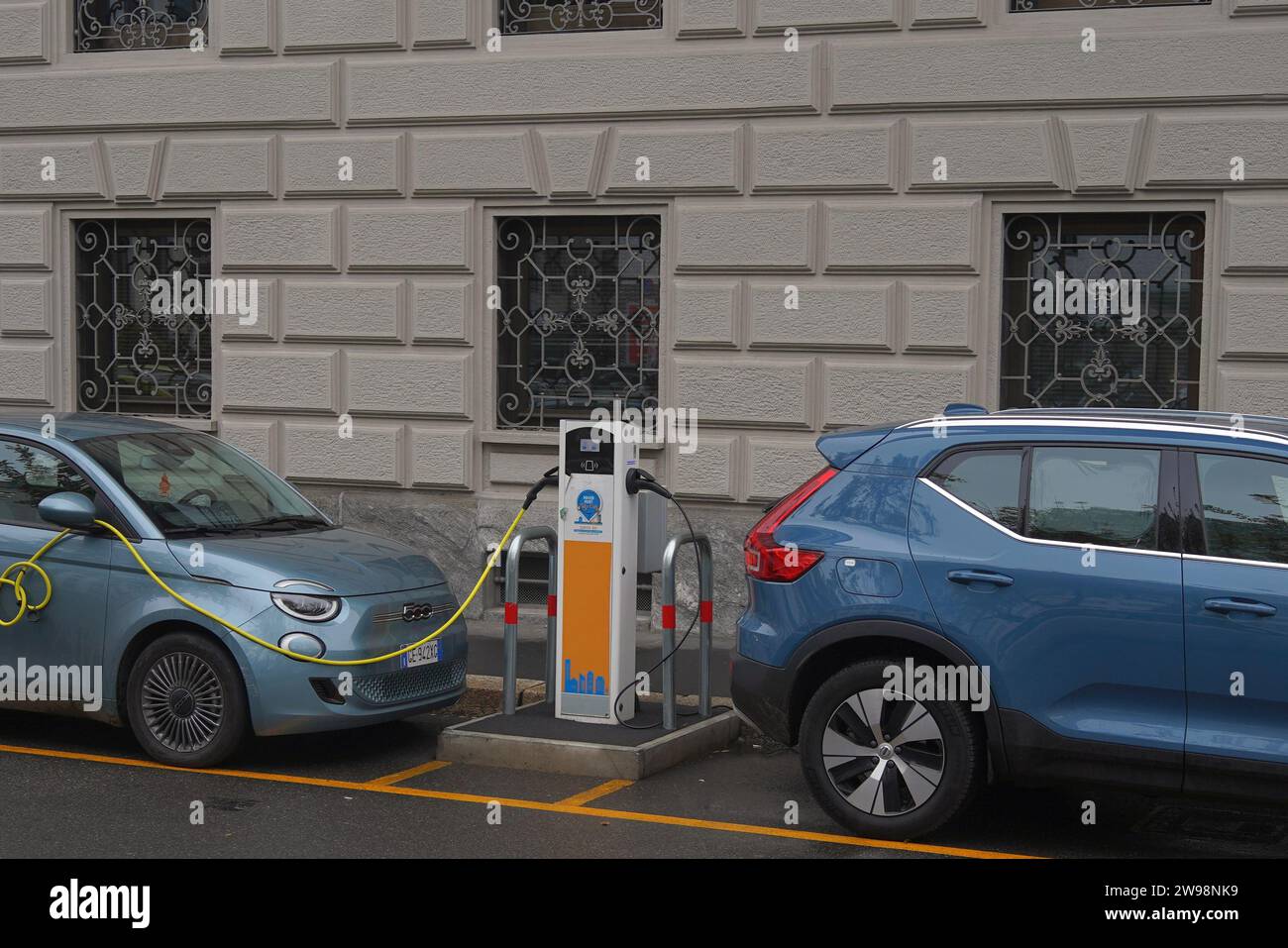 An electric  charging point being used by two cars in Milan, Italy Stock Photo