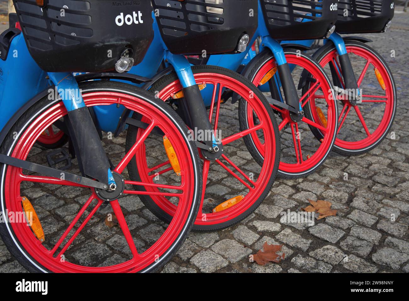 Public Bikes with red wheels lined up in public in Milan, Italy Stock Photo