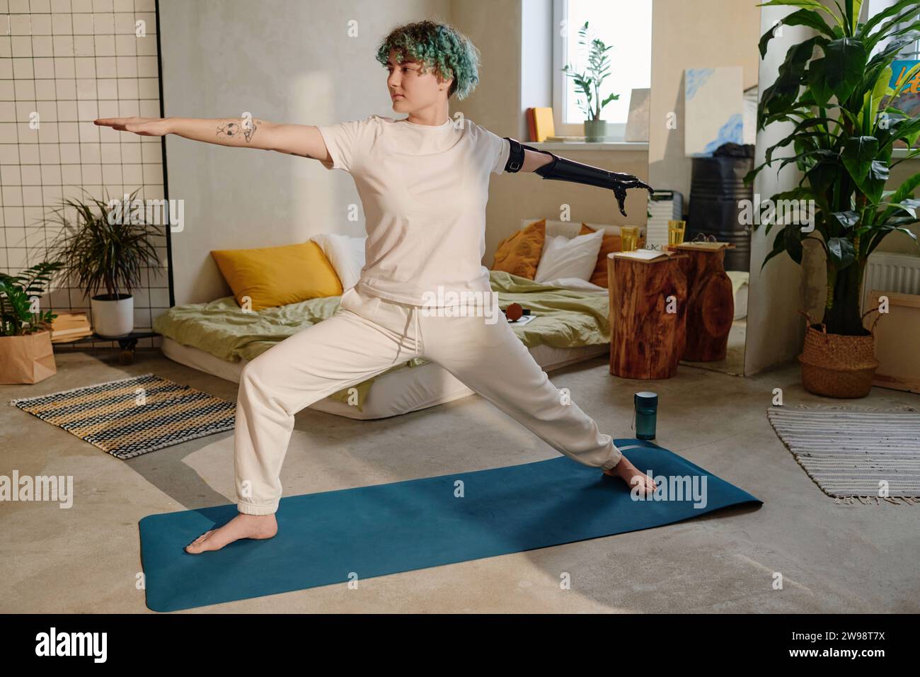 Amputee girl practicing warrior yoga position at home Stock Photo