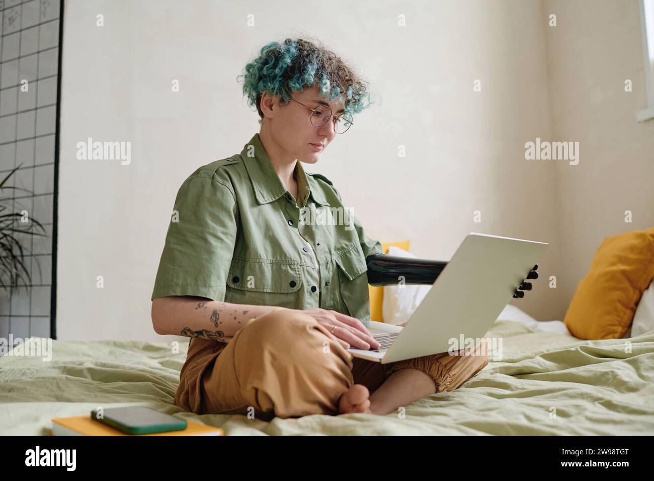 Serious young woman with prosthetic arm working from home Stock Photo