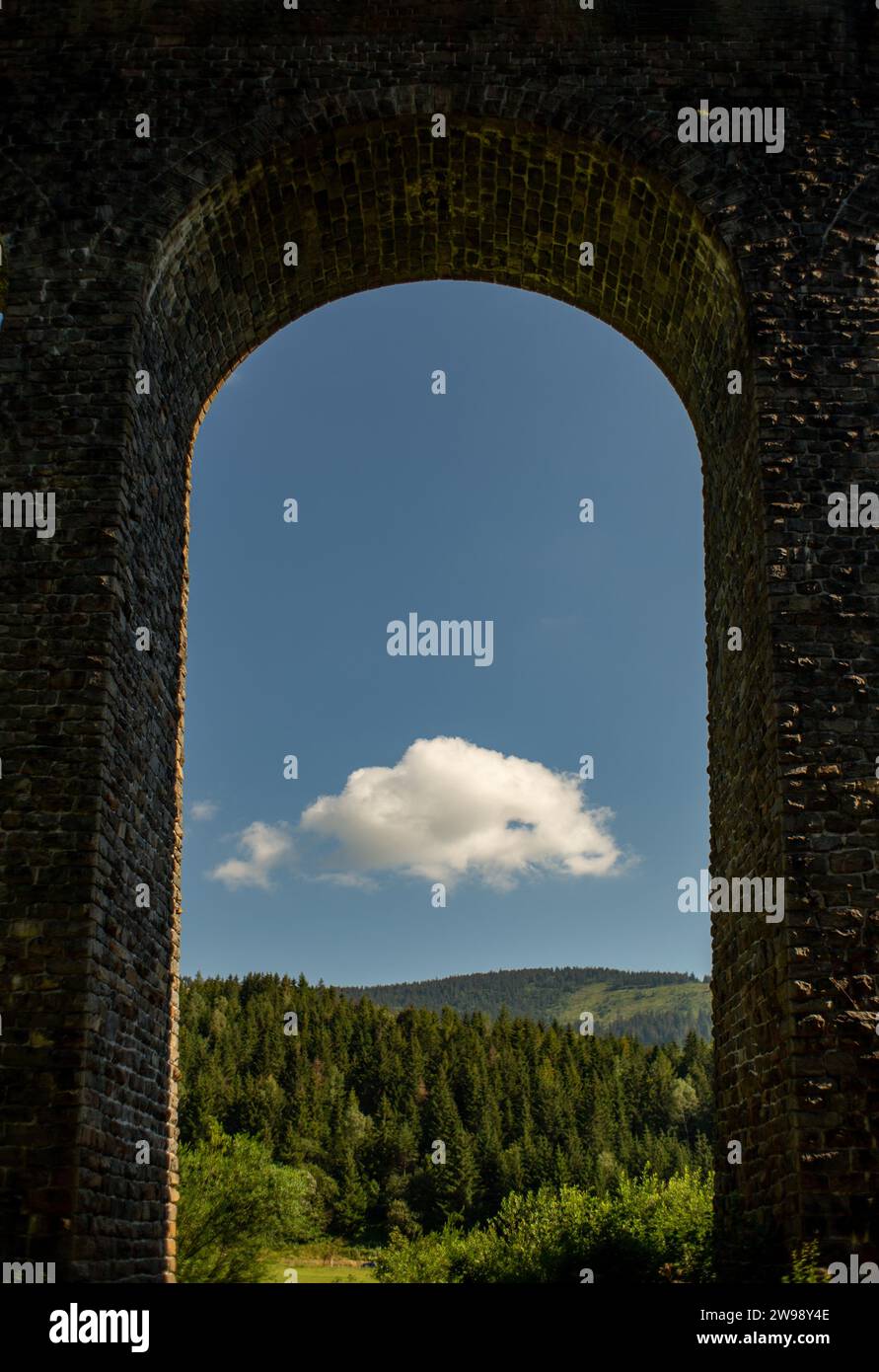The blue sky and green forest seen through a stone arch Stock Photo - Alamy