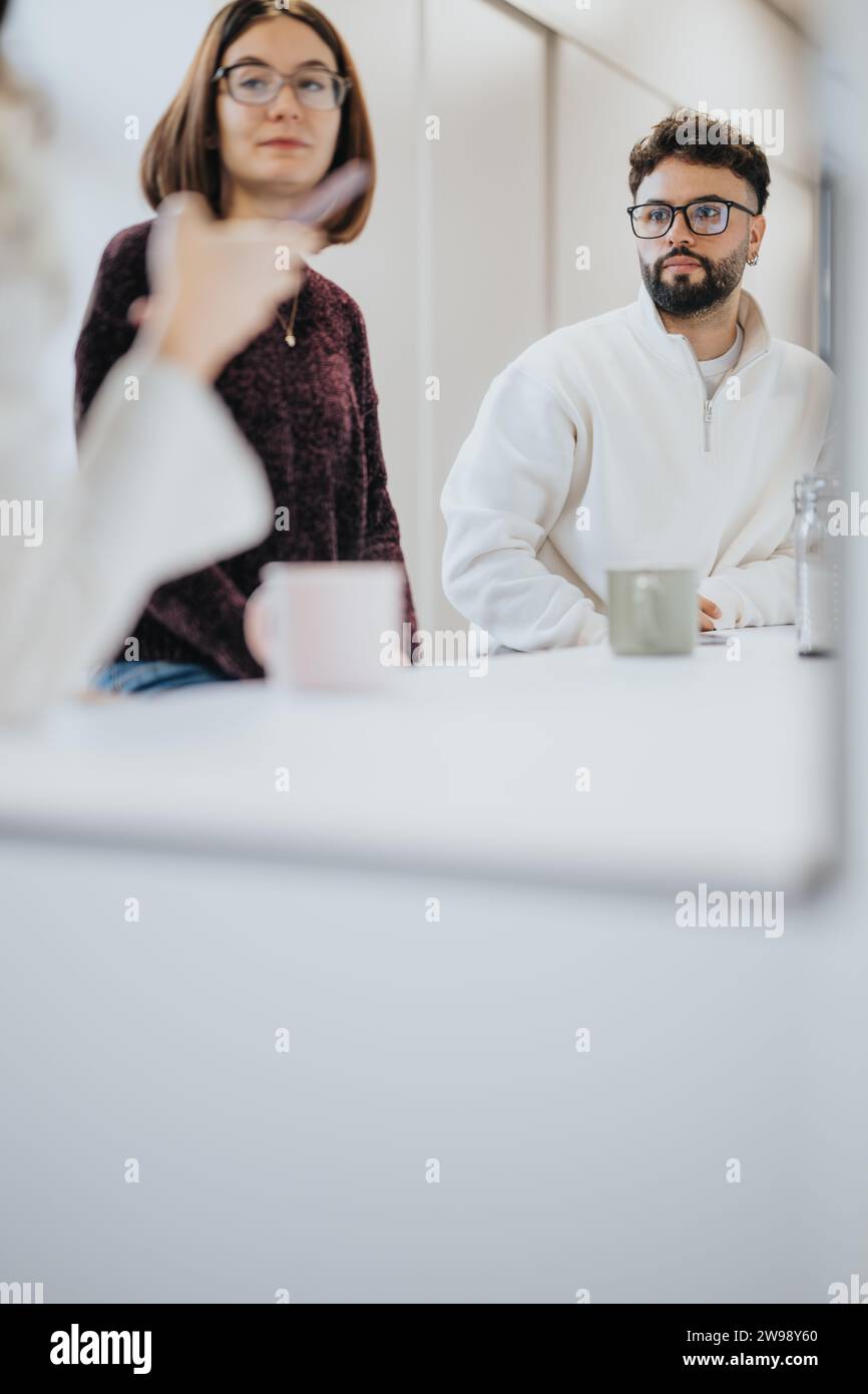 Colleagues in a modern kitchen discussing projects over coffee. A positive atmosphere for a creative team, focused on business growth and success. Stock Photo