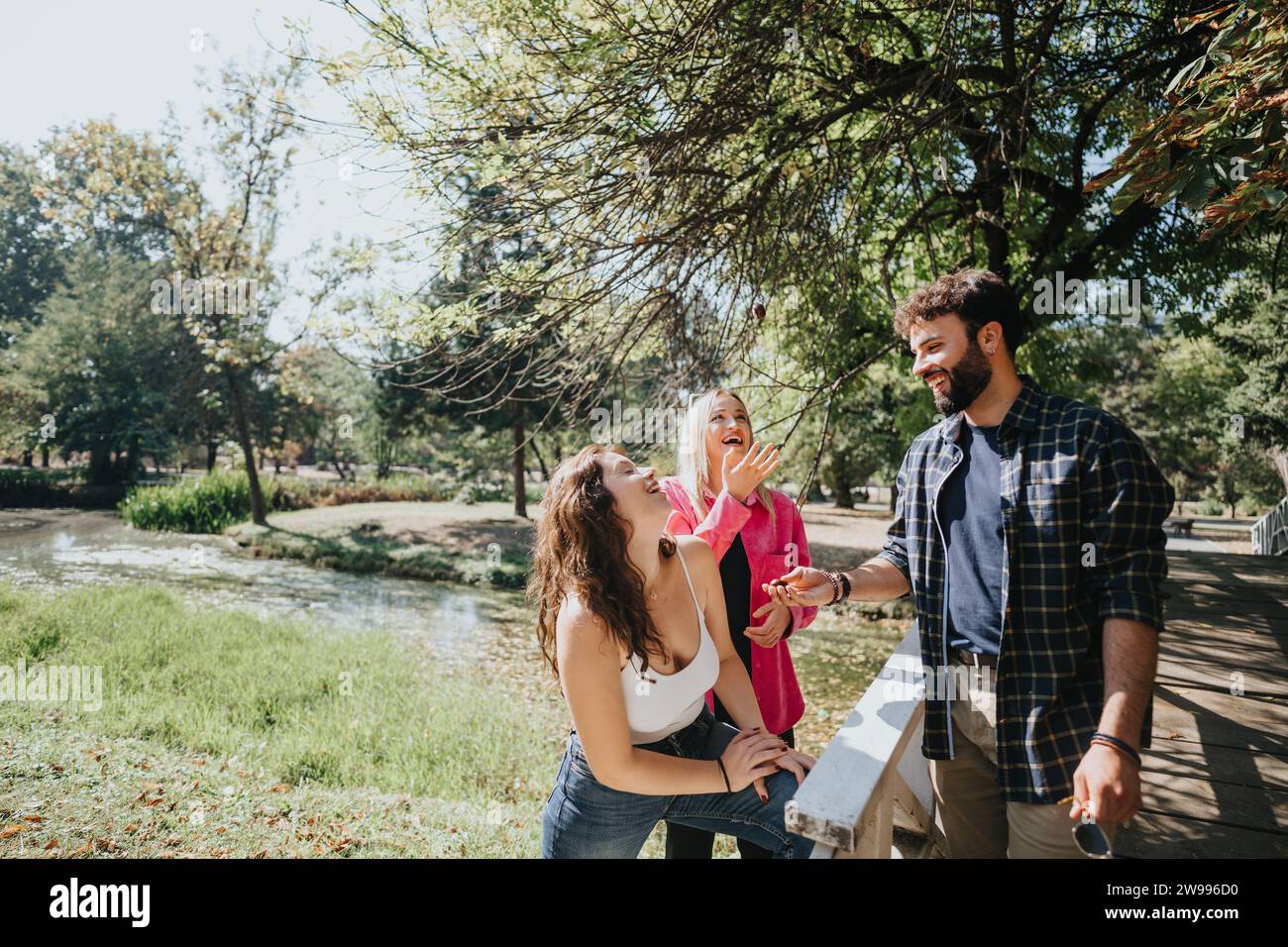 Carefree friends enjoy a sunny day in a green park, talking, laughing ...