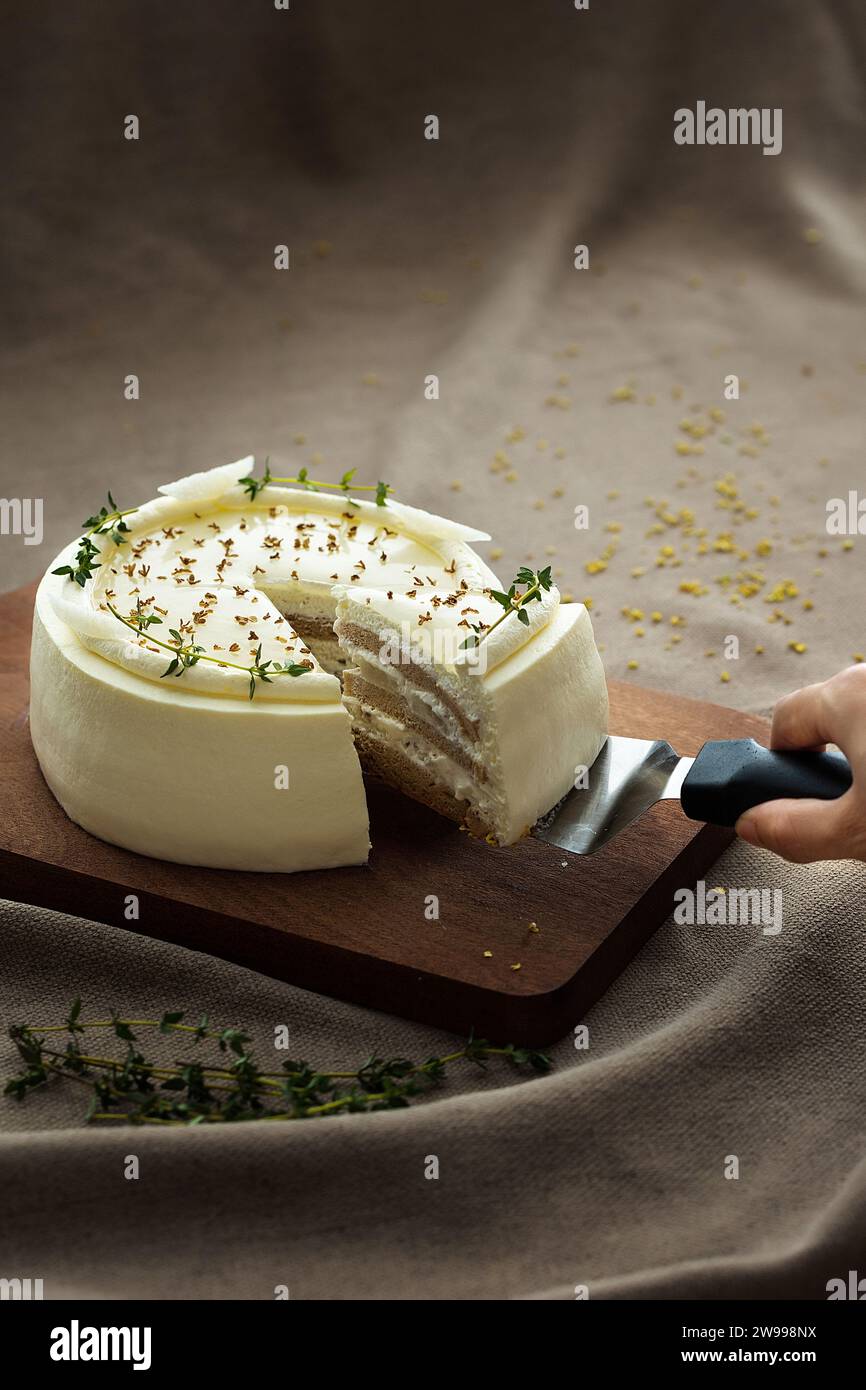 cutting a piece of decadent cake with a sharp knife on a rustic wooden cutting board Stock Photo