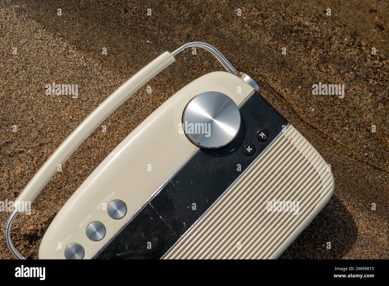 A white, vintage-style radio sitting atop a wooden floor surrounded by a black and white checkered pattern Stock Photo