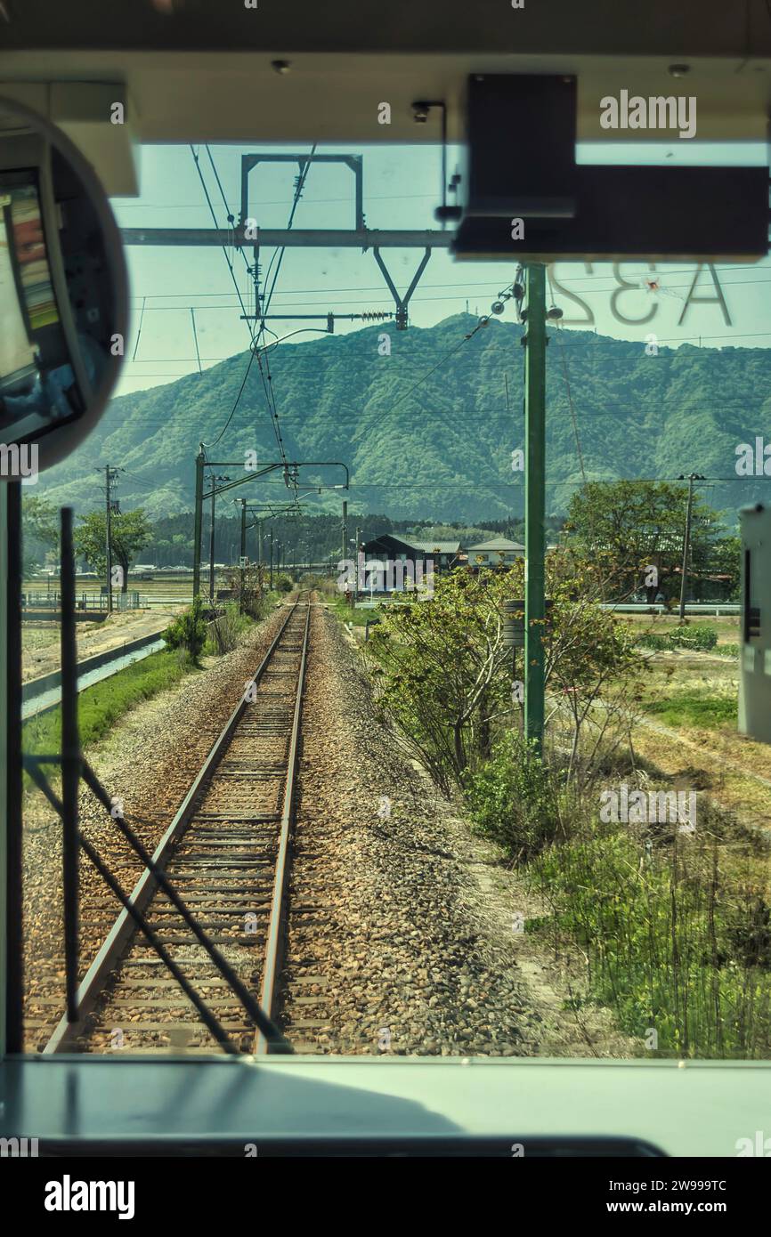 View of the train track from the front cabin of the train. Photo taken in Niigata prefecture on the JR Yahiko Line. Stock Photo