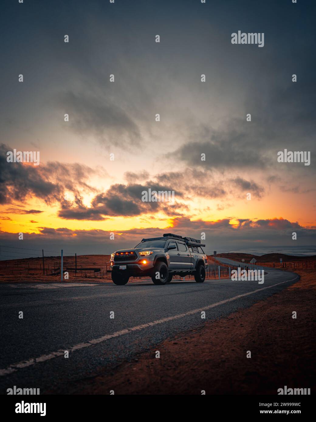 An SUV at sunset, illuminated by the warm golden rays of the setting sun Stock Photo
