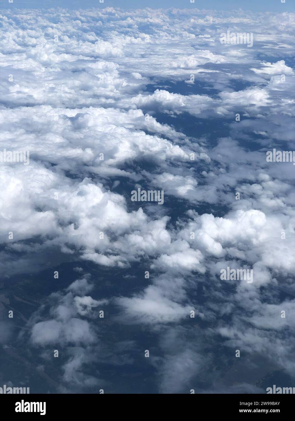 An aerial view of a cloudy sky seen through the window of an airplane ...