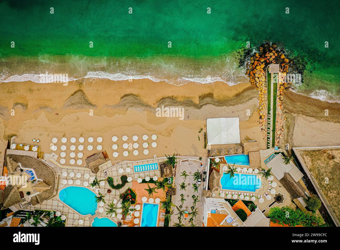 Drone top down shot of the beach and colorful ocean, hotel and pools