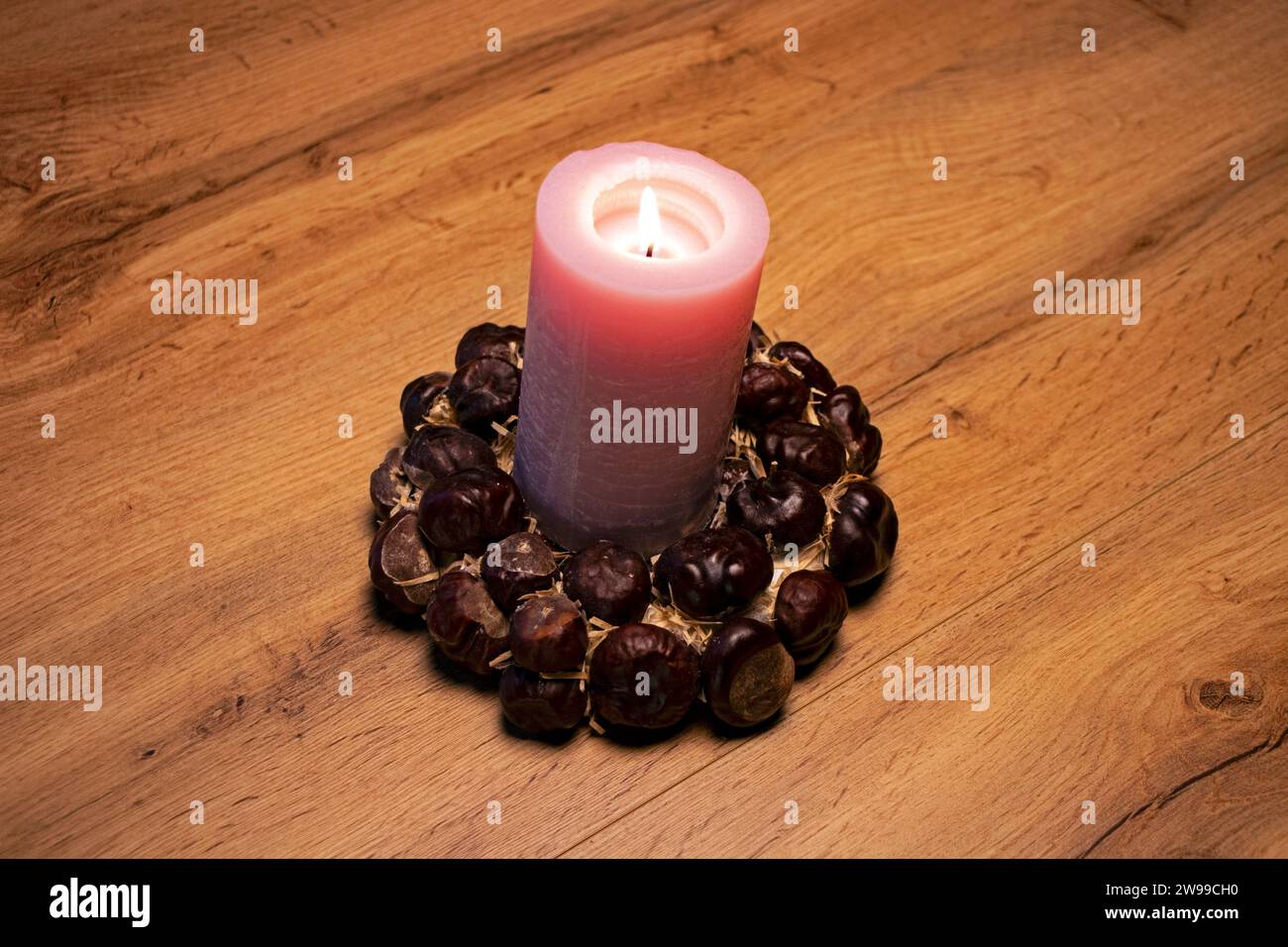 The decorative pinky candle with flame on chestnut ring on close-up christmas scene Stock Photo