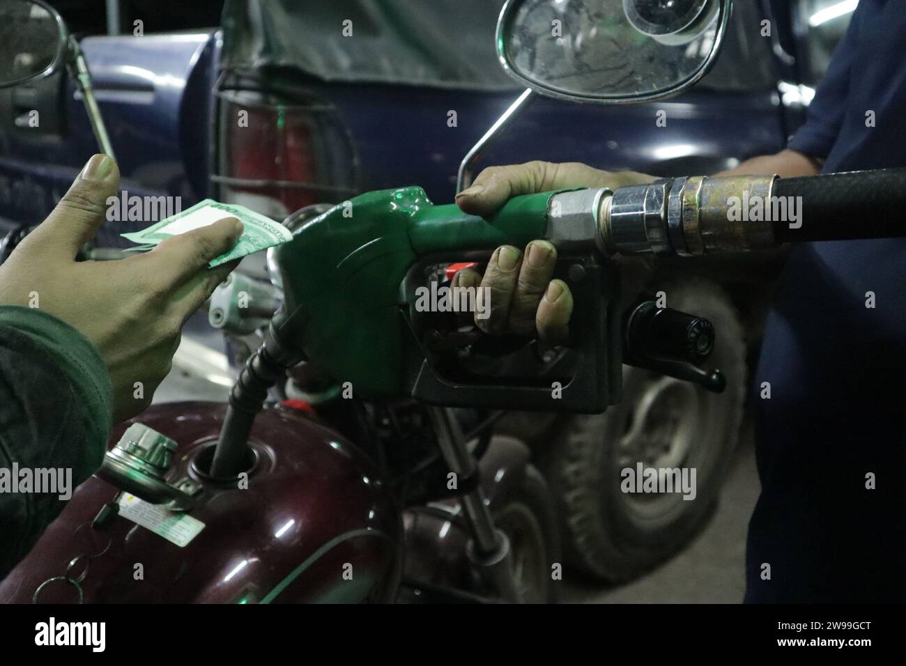 Dhaka, Bangladesh. 26th Dec, 2023. A motorcycle rider holds Bangladeshi Taka bank notes to pay for fuel at a fuel station in Dhaka. (Credit Image: © MD Mehedi Hasan/ZUMA Press Wire) EDITORIAL USAGE ONLY! Not for Commercial USAGE! Stock Photo
