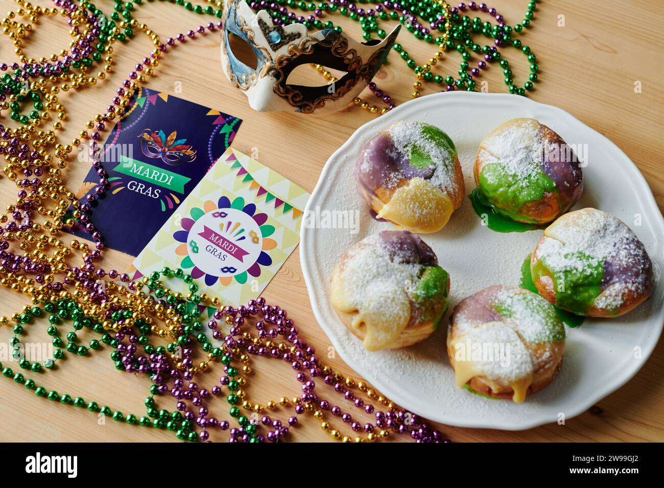 Plate with several homemade berliner donuts standing among other symbols of Mardi Gras such as postcards, venetian mask and beads Stock Photo