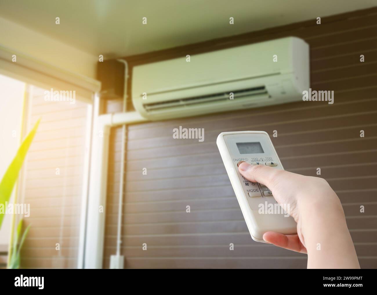 Hand hold remote control directed on the air conditioner Stock Photo
