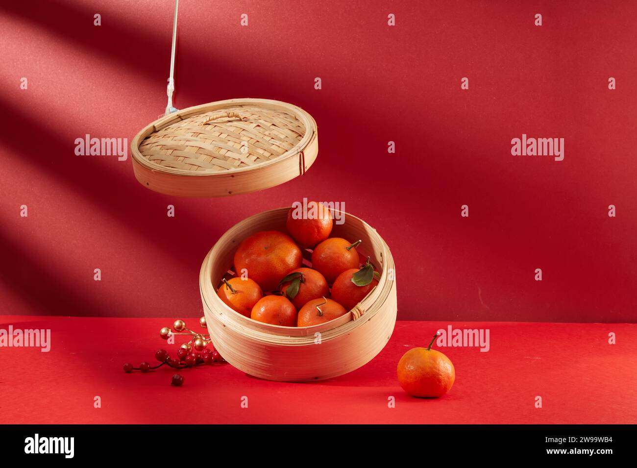 Tangerines are stored in a bamboo steamer on a red background