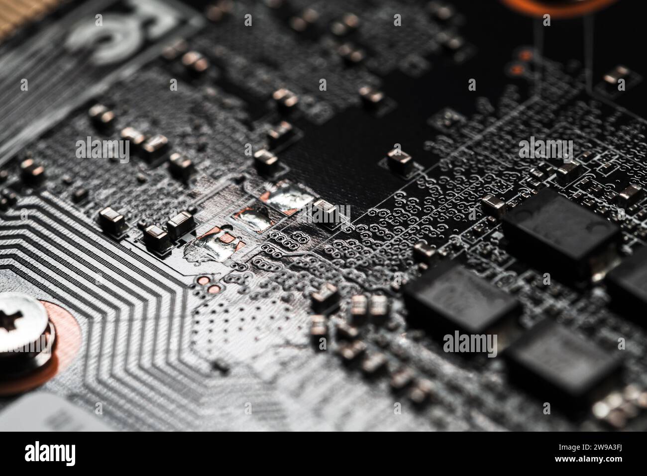 Black printed circuit board with microchips and capacitors, macro photo