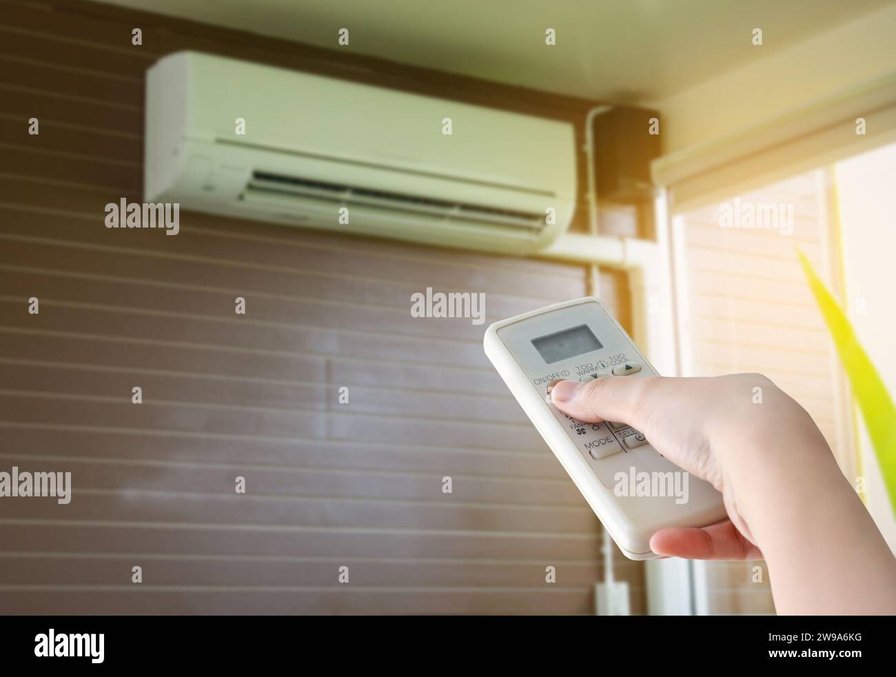 Hand hold remote control directed on the air conditioner Stock Photo
