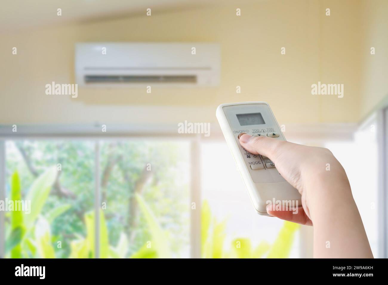 Hand hold remote control directed on the air conditioner Stock Photo