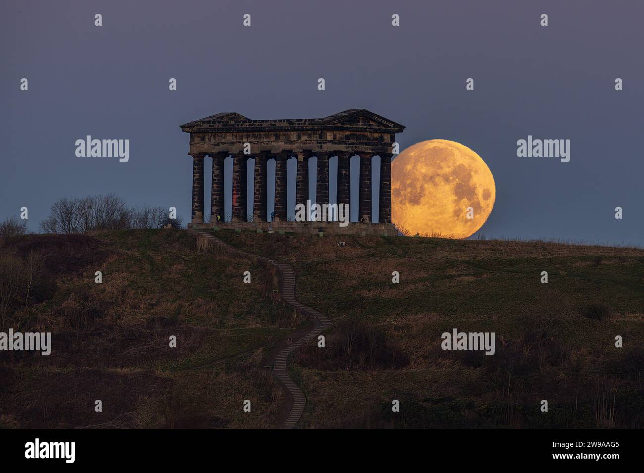 People look on as The Full Cold Moon sets at Penshaw Monument, Near