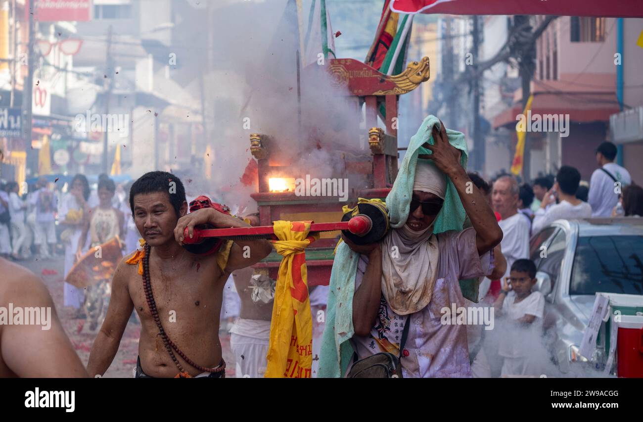 Devotees carry an idol on a palanquin amid exploding fire-crackers during a street procession at the annual Vegetarian Festival in Phuket Town, Thaila Stock Photo