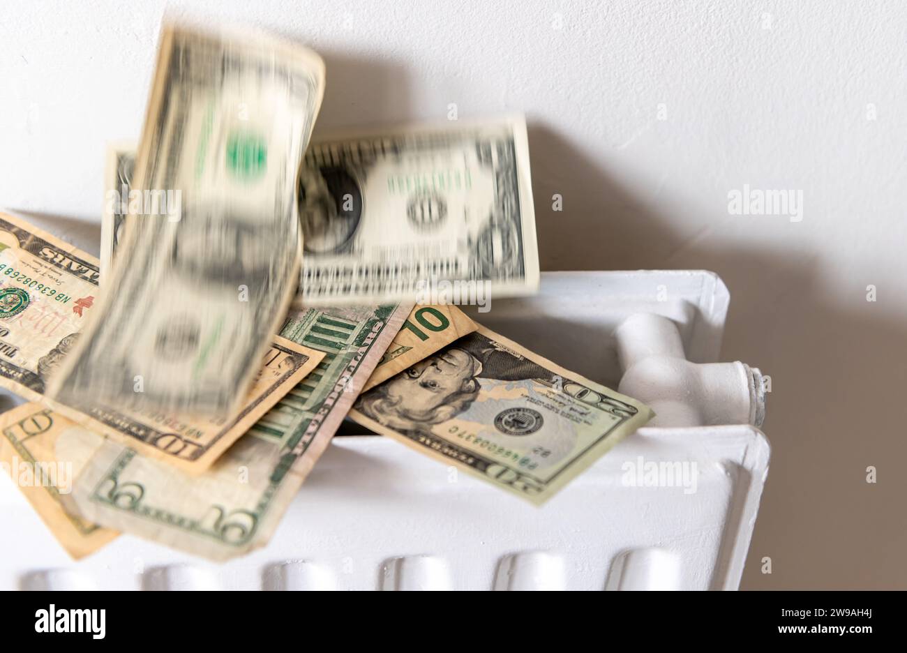 A heating, energy cost concept with a pile of US Dollars rising from a central heating radiator. Stock Photo