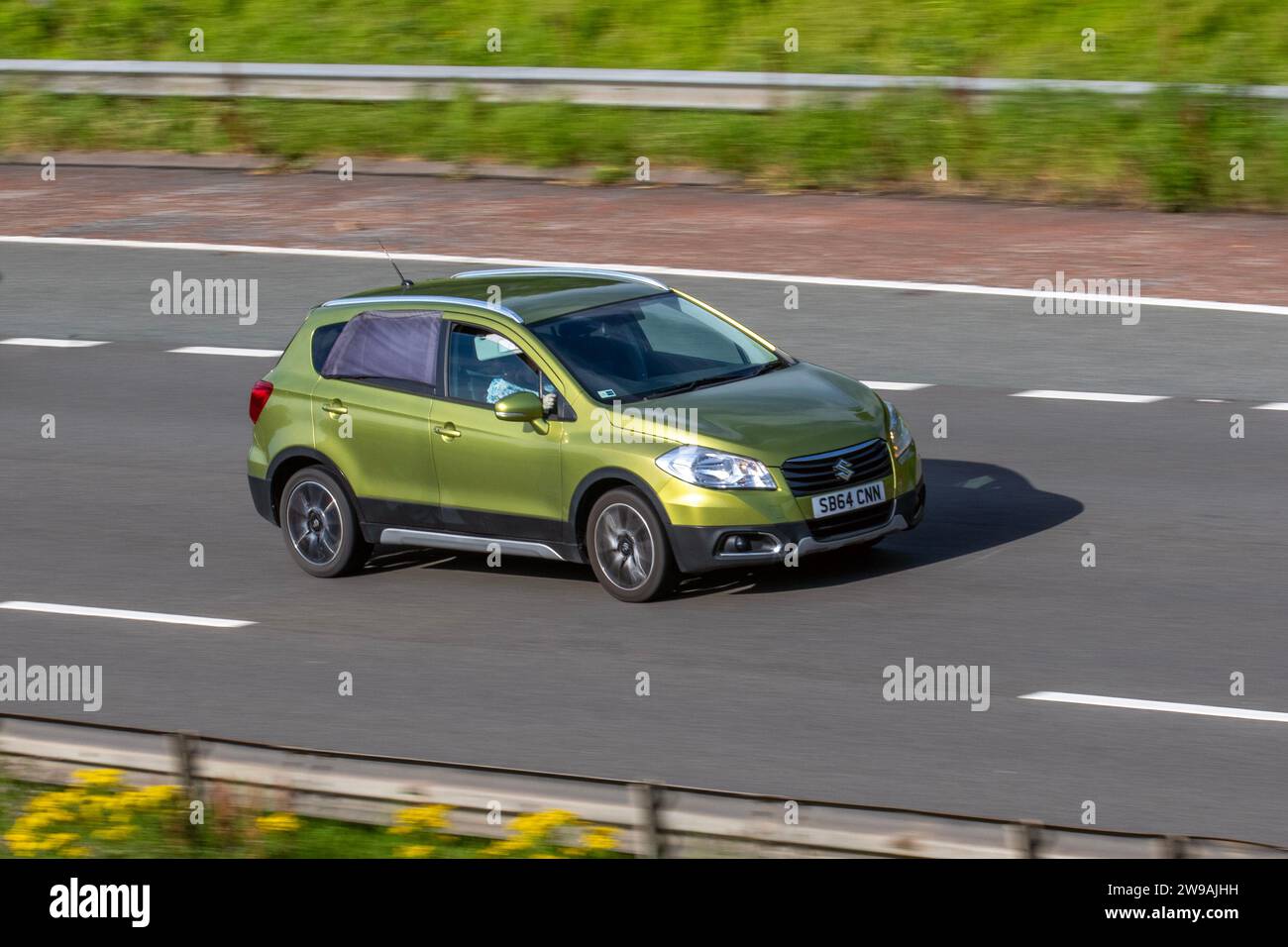 2015 Green Suzuki SX4 SZ-T 1586 cc Petrol 8 speed manual, subcompact car and crossover, Sports X-over 4 Seasons; travelling at speed on the M6 motorway in Greater Manchester, UK Stock Photo