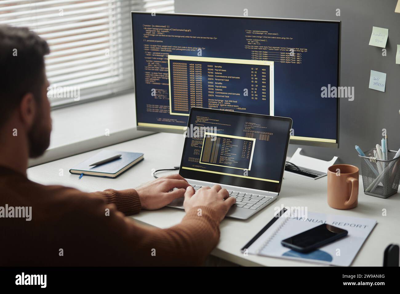 Over shoulder view of software programmer using computer in office and writing code, copy space Stock Photo