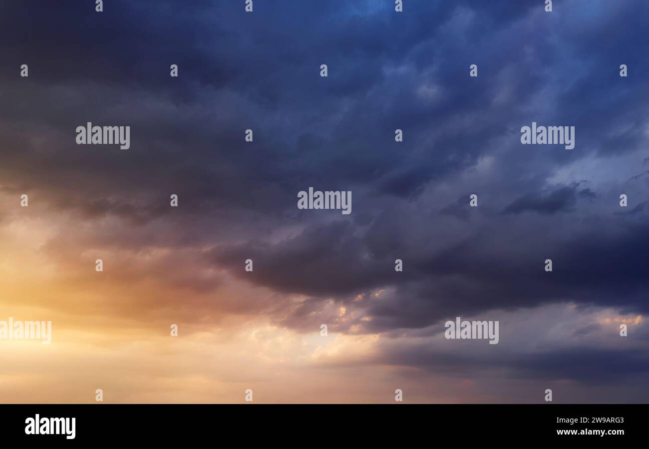 Dramatic sunset sky with dark rainy clouds and bright sunshine. Stock Photo