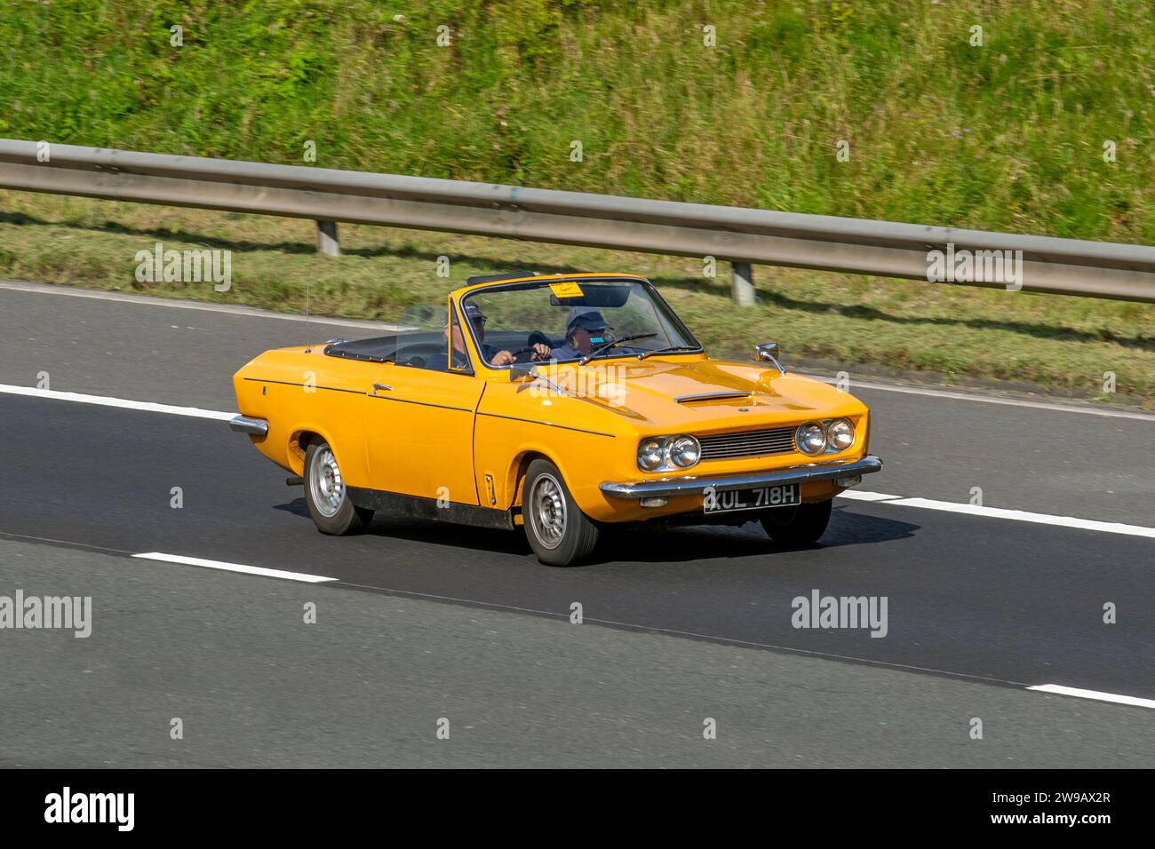 1969 60s sixties Yellow GT4S Bond Equipe 2-litre, English 2+2 sports car cabriolet, 1998 cc 95 bhp (71 kW) six-cylinder engine; travelling at speed on the M6 motorway in Greater Manchester, UK Stock Photo