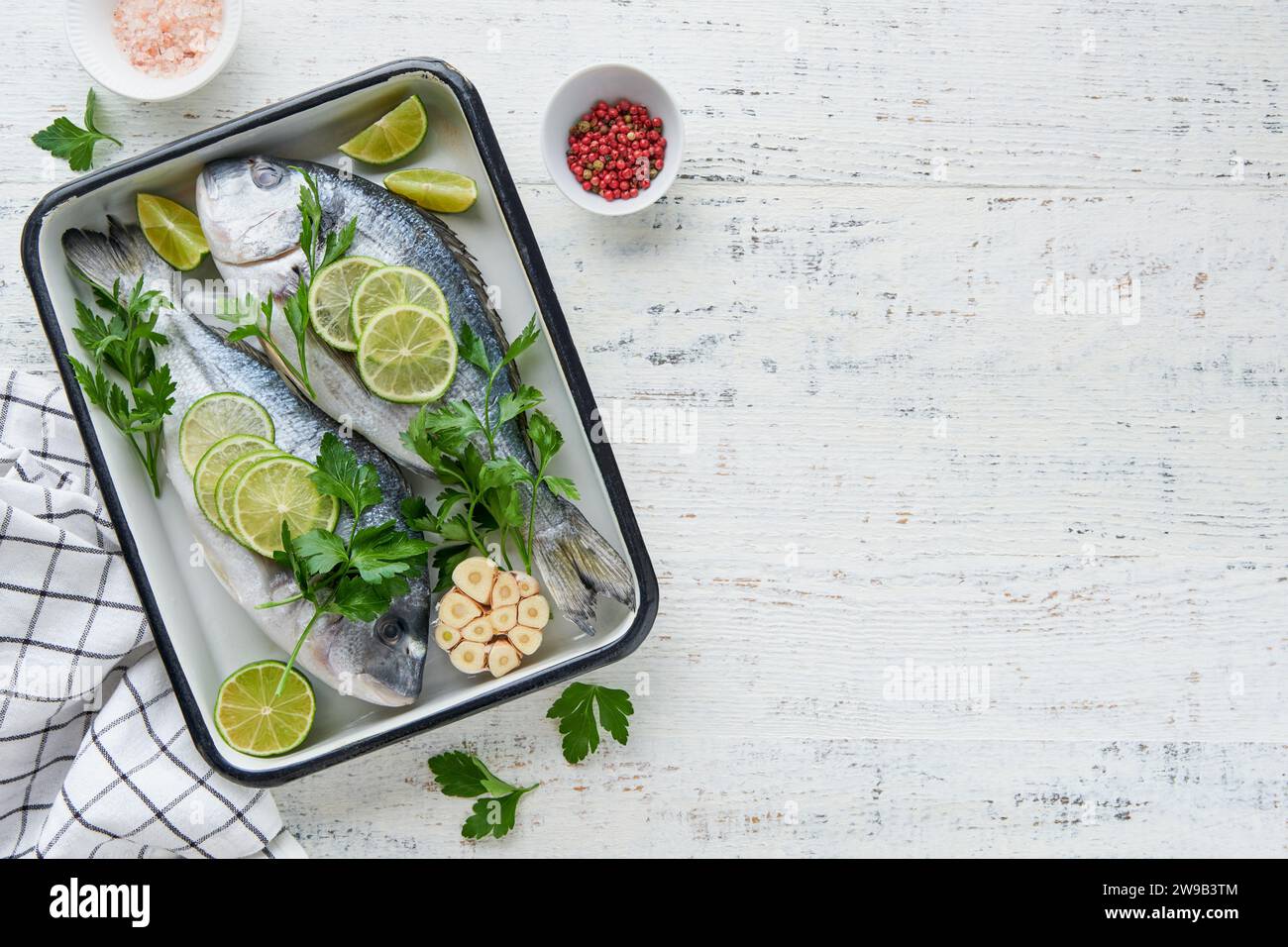 Raw fresh. Fresh raw dorado with lemon, lime, parsley and salt on old wooden white background ready for cooking. Sea bream, dorado. Seafood, healthy f Stock Photo