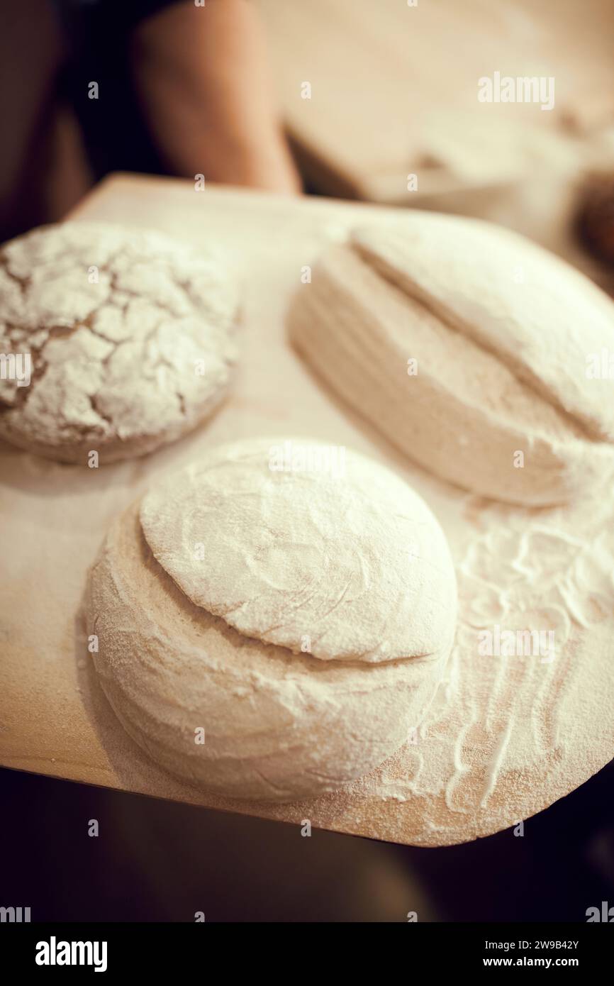 three loaves of bread sitting on top of wooden cutting board. bread