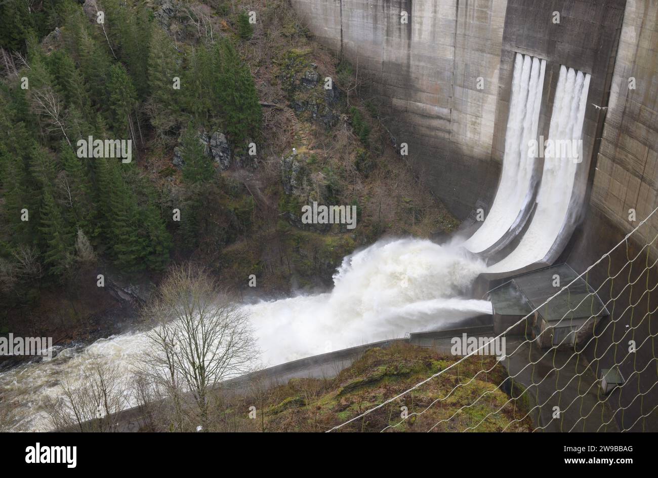Altenau, Germany. 26th Dec, 2023. The spillway releases water from the completely filled Okertal dam in the Harz Mountains. Credit: Julian Stratenschulte/dpa/Alamy Live News Stock Photo