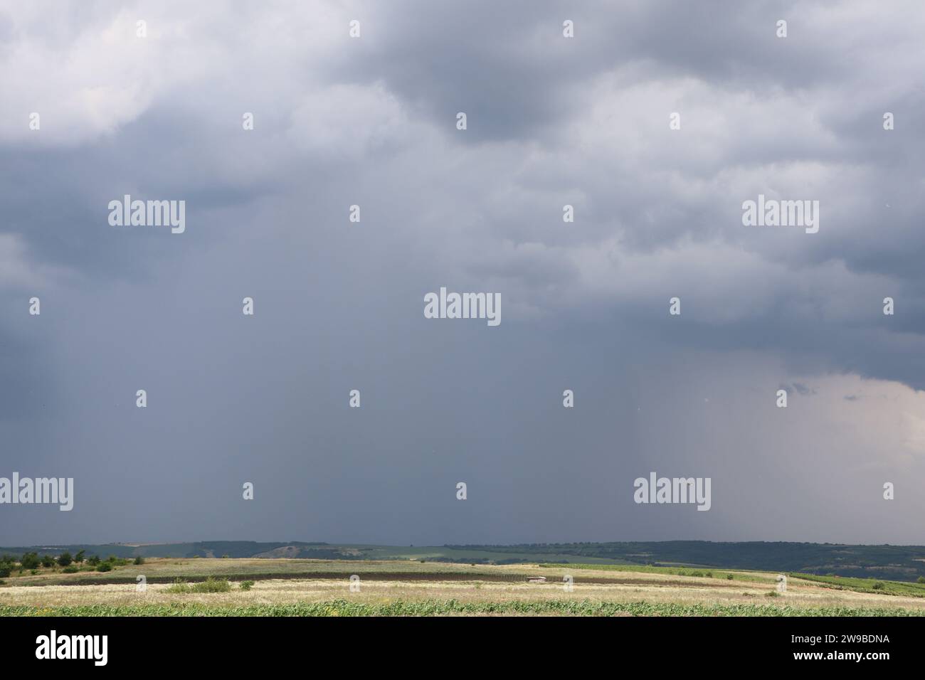 A dark storm cloud hangs far over the valley and heavy rain is falling(02)