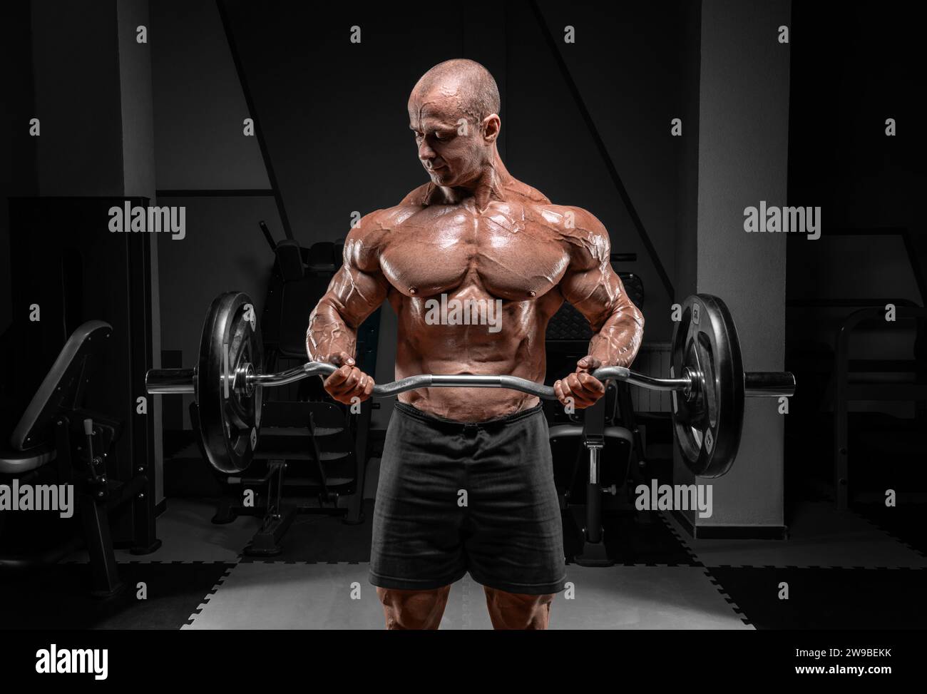 Professional weightlifter posing in the gym with a barbell in his hands. Classic bodybuilding
