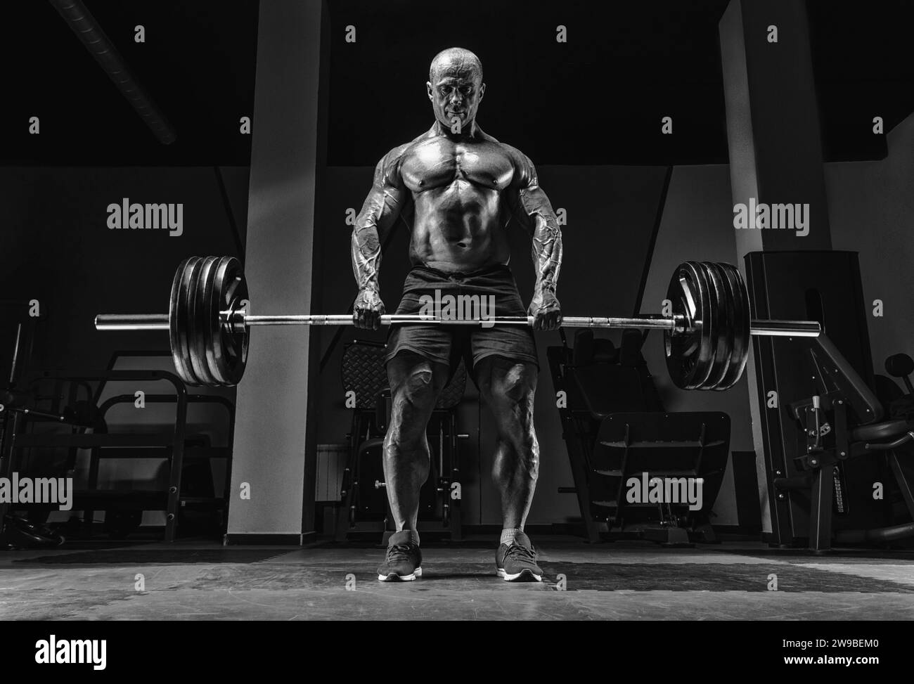 Muscular man stands with a barbell in his hands. Deadlift. Bodybuilding concept. Mixed media Stock Photo