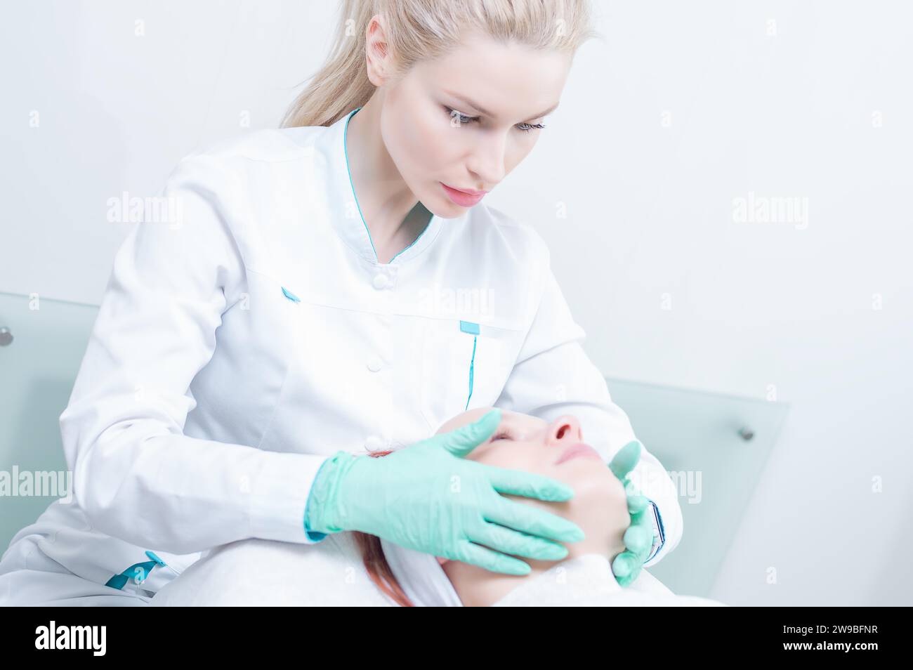 Doctor in a dressing gown examines the patient's face. Plastic surgery concept. Mixed media Stock Photo