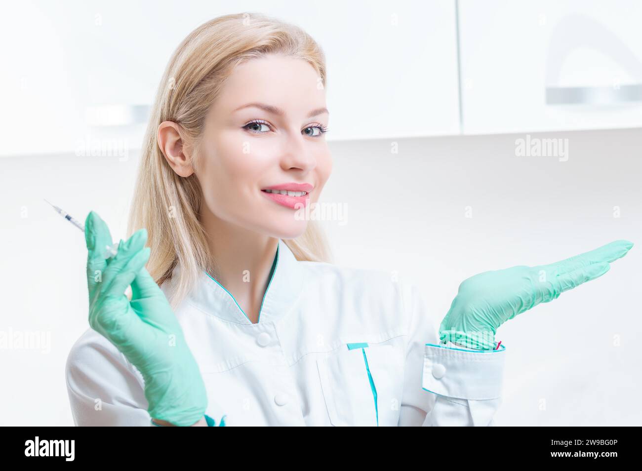 Portrait of a blonde girl in a medical gown with a syringe in her hands. Medical center advertisement. Mixed media Stock Photo