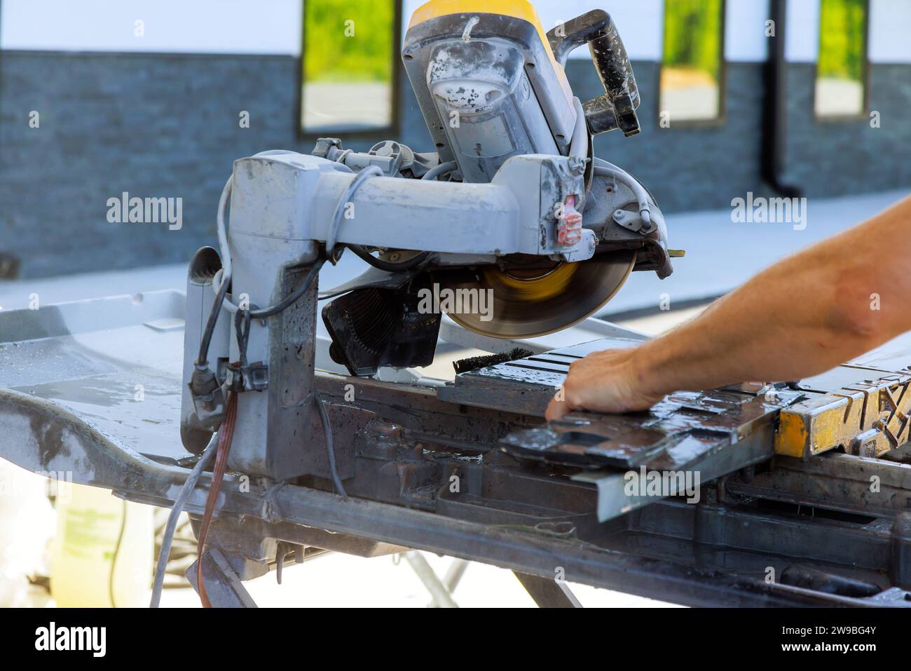 Tiler using diamond blade saw machine to cut ceramic tile Stock Photo